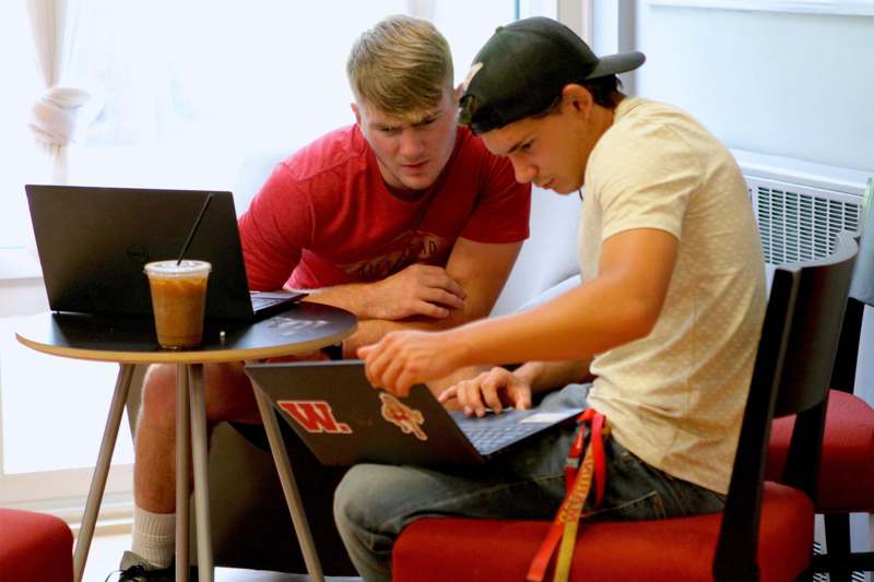 a couple of men looking at a laptop