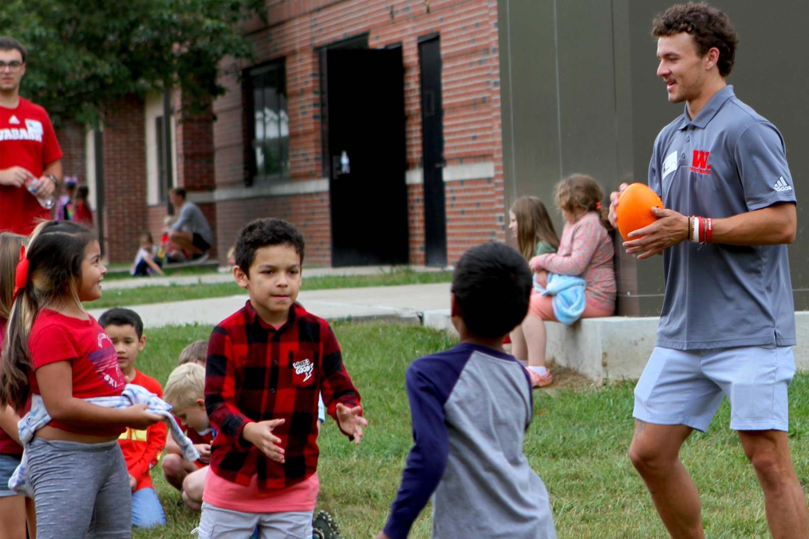 a man holding an orange object in front of a group of children