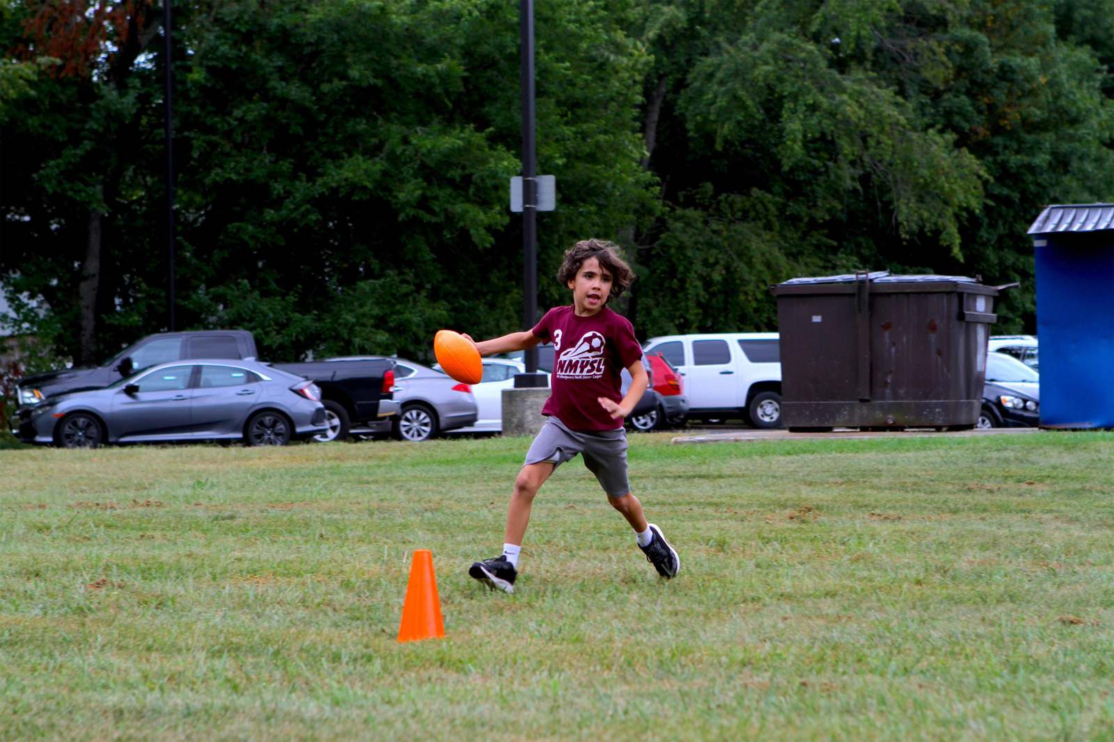 a boy running with an orange frisbee