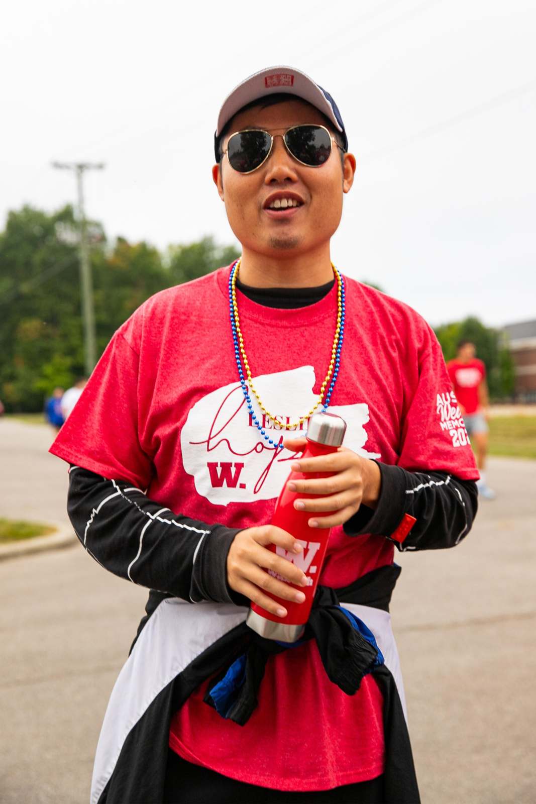 a man wearing a red shirt and sunglasses holding a red bottle