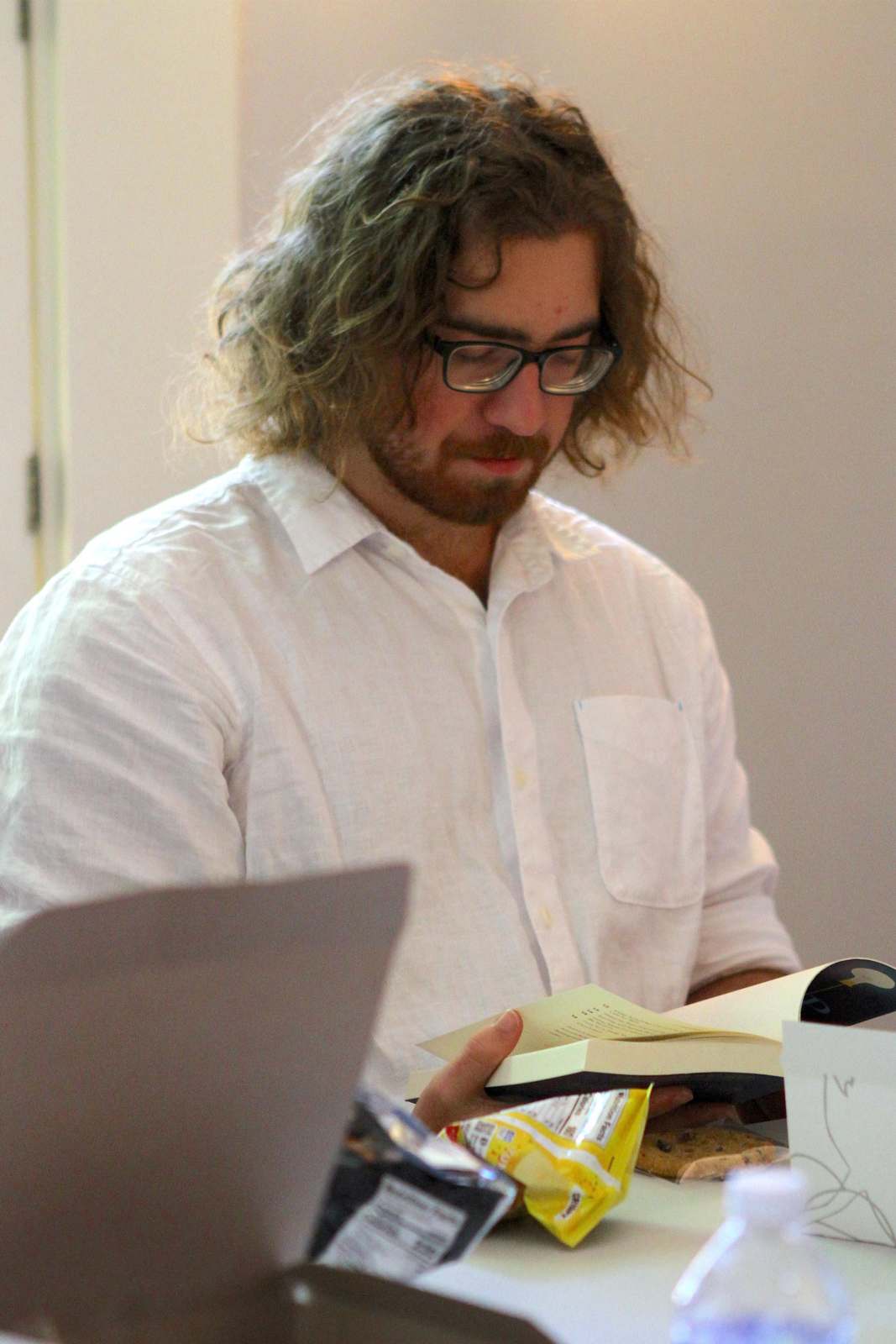 a man with long hair and glasses reading a book