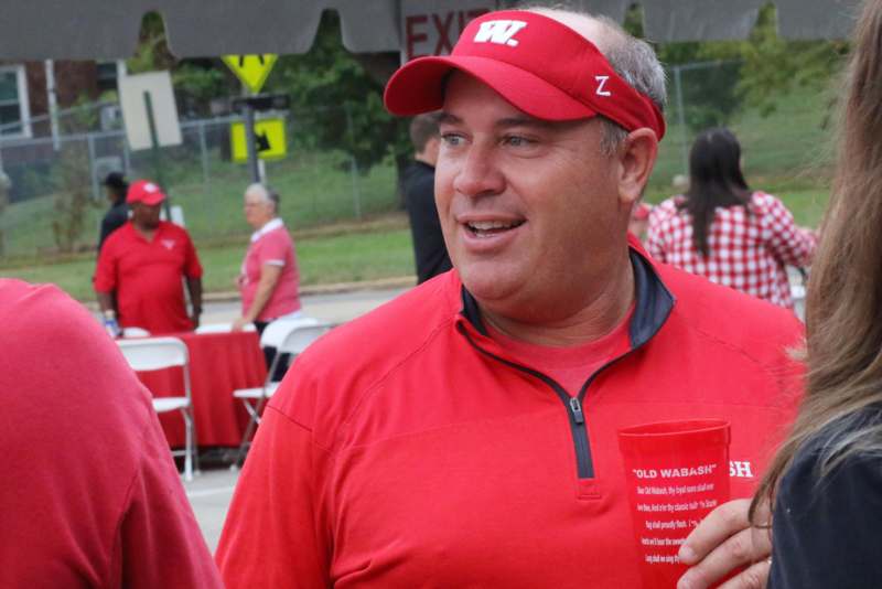 a man in red shirt and cap holding a cup