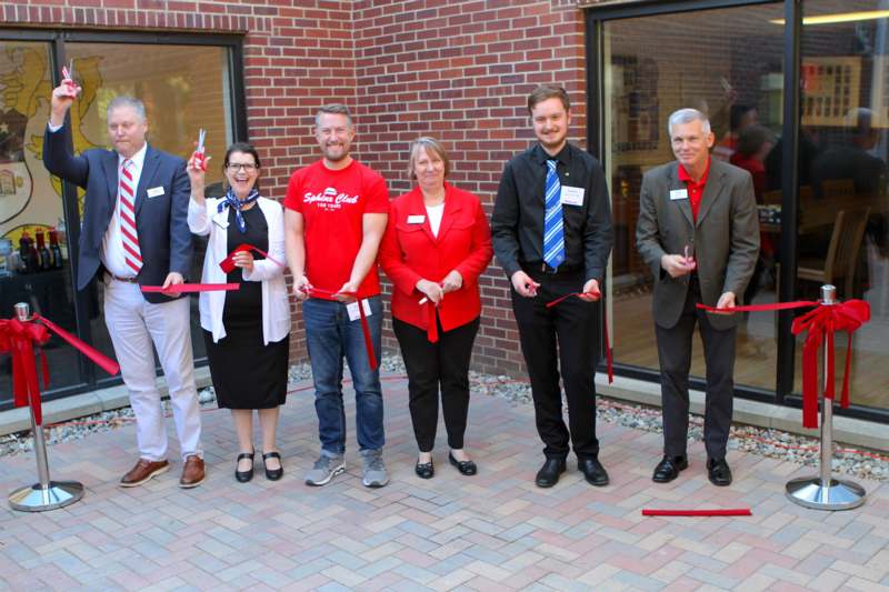 a group of people cutting red ribbon