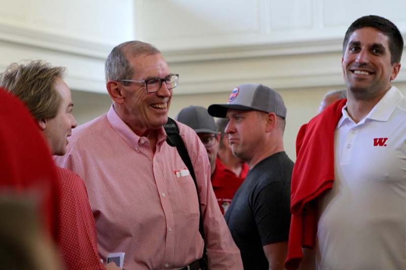 a man in a red shirt and glasses smiling
