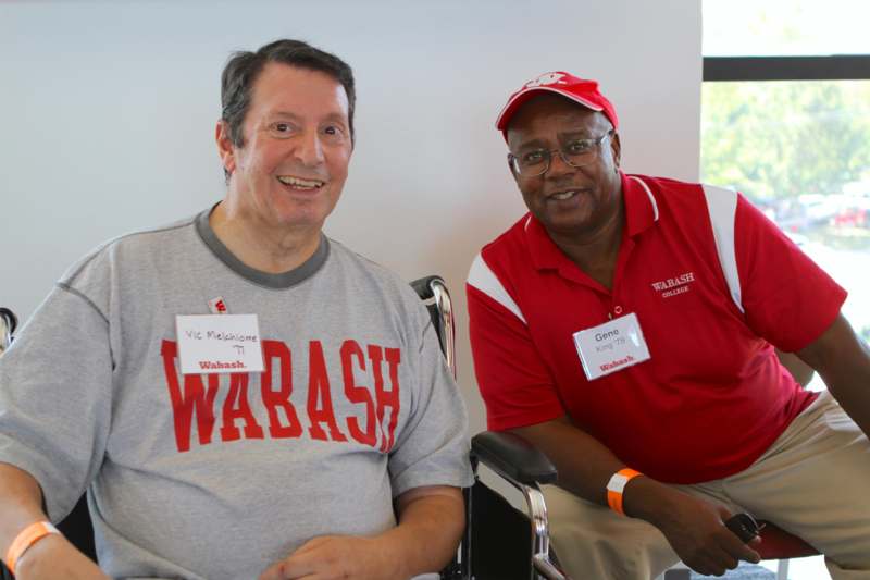 a man in a wheelchair next to a man in a red shirt