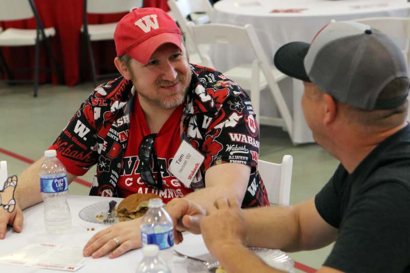 a man in a red hat and a red shirt sitting at a table with a hamburger