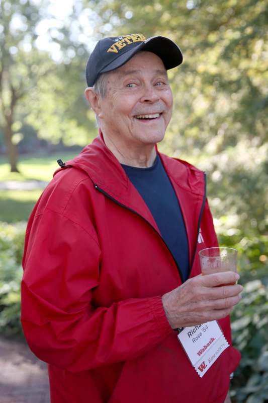 a man in a red jacket holding a drink