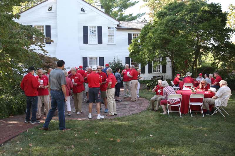 a group of people in red shirts outside a house