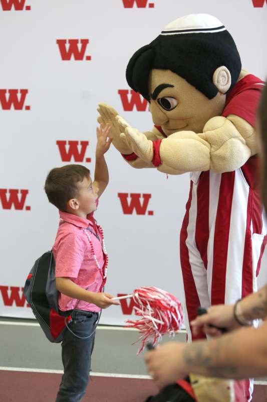 a boy high fiving a mascot
