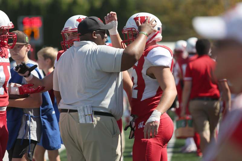 a football coach giving a high five to a football player