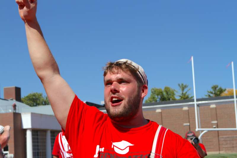 a man in red shirt with his hand up