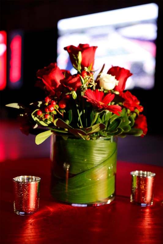 a vase of red flowers and candles