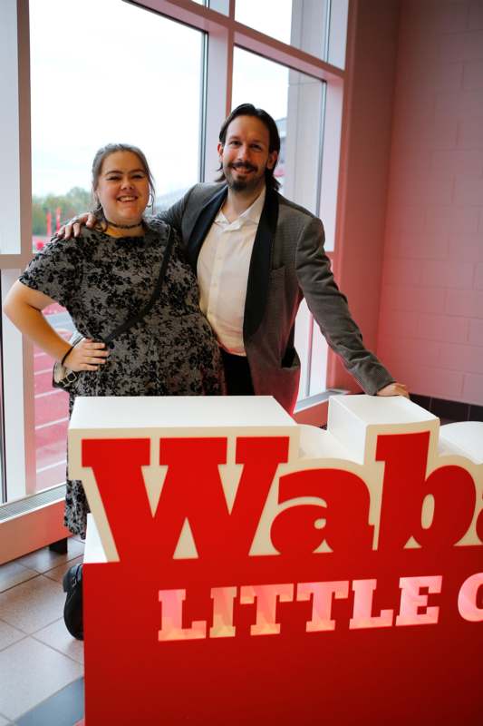 a man and woman standing next to a sign