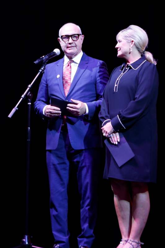 a man and woman standing next to a microphone