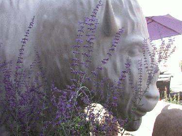 a statue of a buffalo with purple flowers