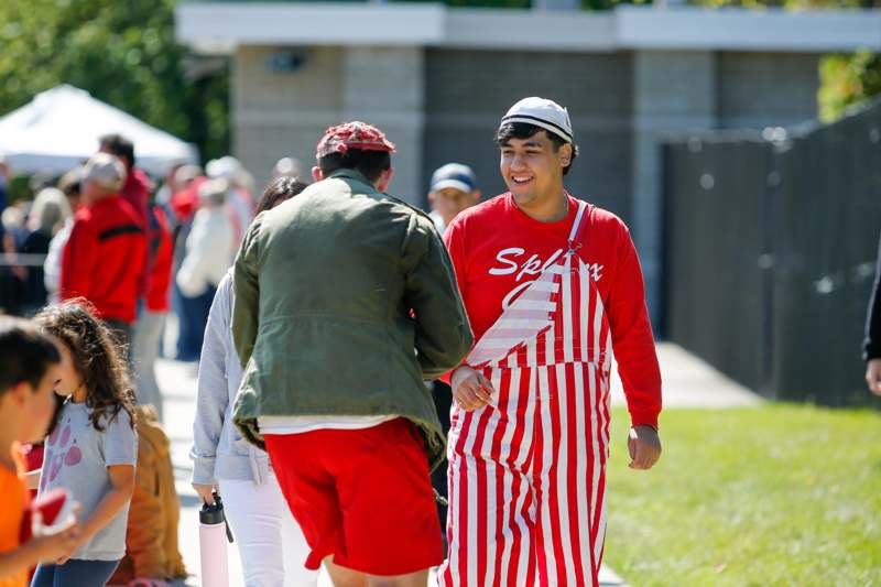 a man in red and white striped overalls walking on a sidewalk