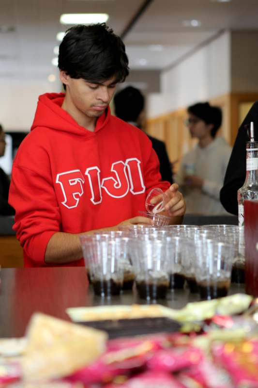 a man in a red sweatshirt pouring liquid into a cup