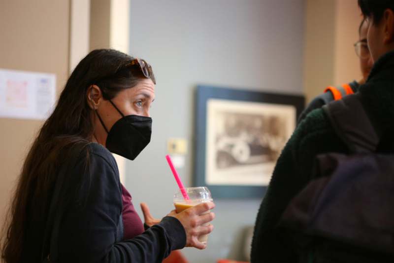 a woman wearing a face mask and holding a drink