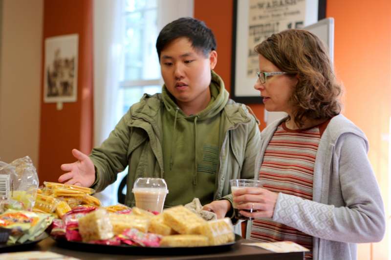 a man and woman standing next to a table with food