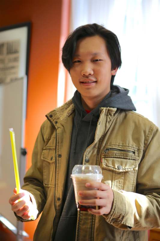 a man holding a straw and a drink