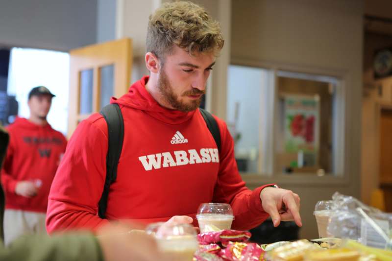 a man in a red sweatshirt pointing at food