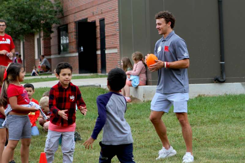 a man holding an orange object in a field with kids
