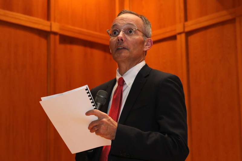 a man in a suit holding a microphone and paper