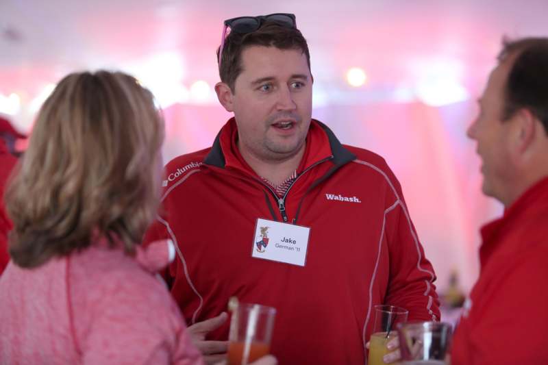 a man in a red jacket talking to a group of people