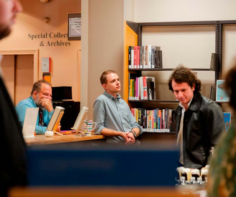 a group of men standing at a counter in a library