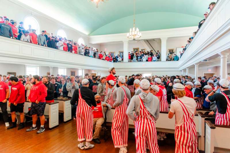 a group of people in striped aprons in a room with a large crowd