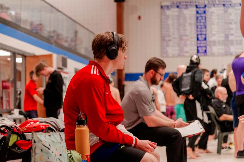 a man wearing headphones sitting in a swimming pool