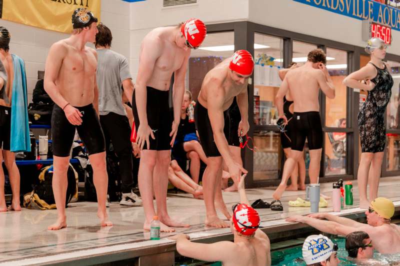a group of swimmers standing next to a pool