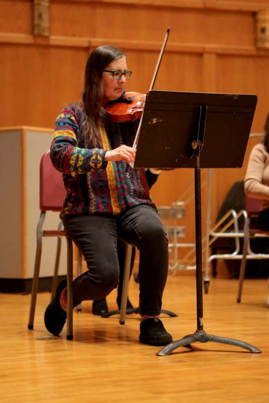 a woman sitting on a chair playing a violin