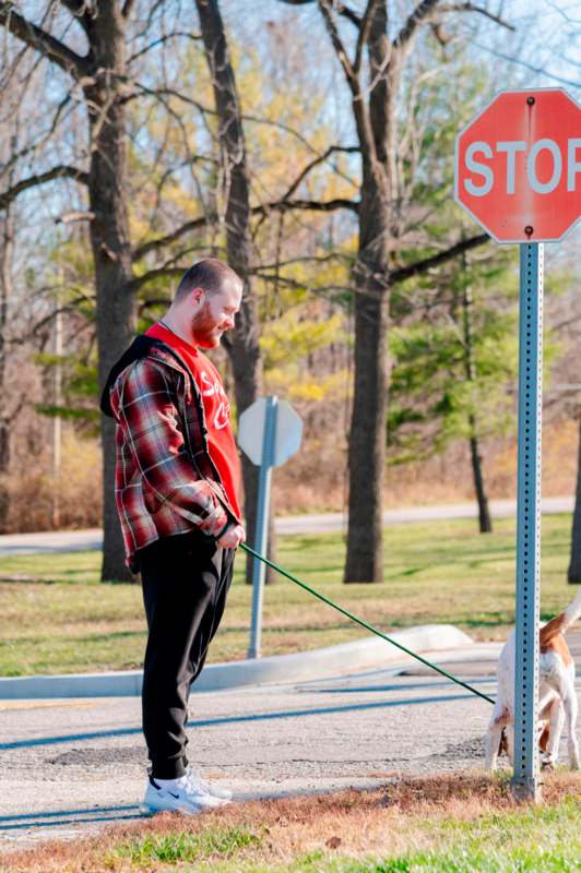 a man walking a dog on a leash next to a stop sign
