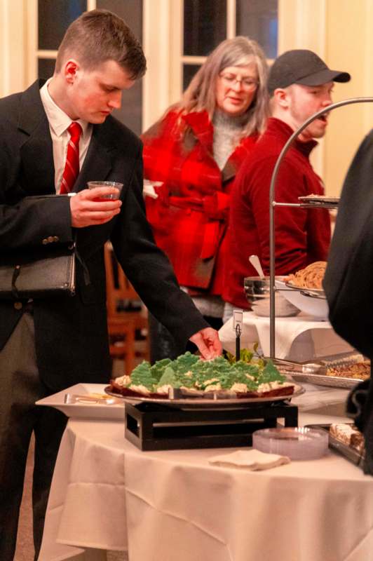 a man in a suit and tie standing next to a plate of food
