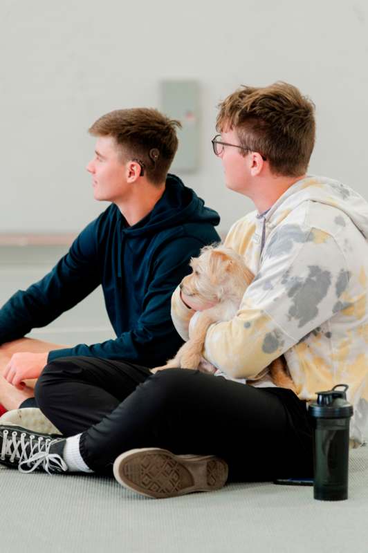 two men sitting on the floor with a dog