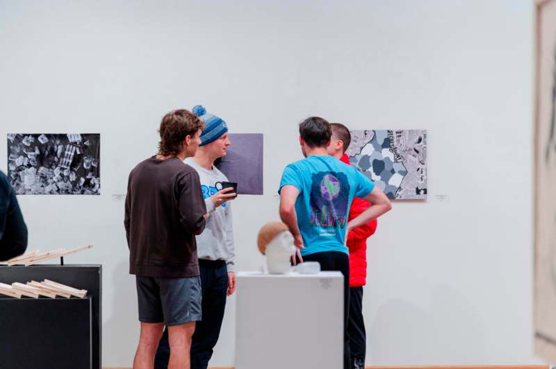a group of people standing in a room with art on the wall