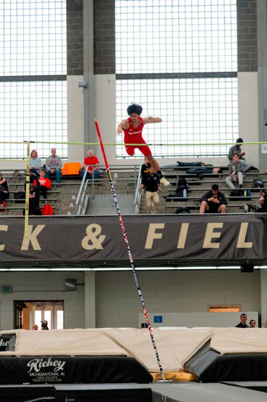 a man jumping over a pole in a gym