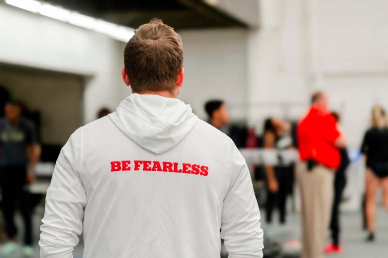 a man wearing a white jacket with red text on it