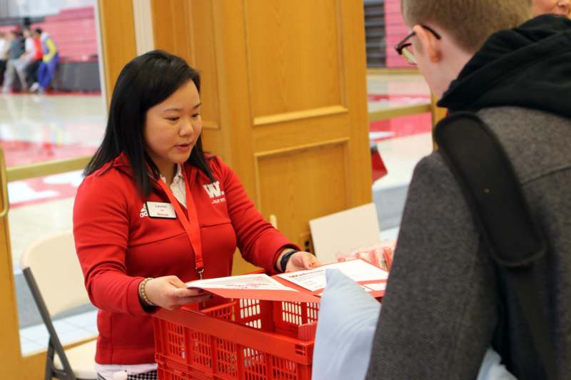 a woman in a red shirt handing a shopping cart to a man