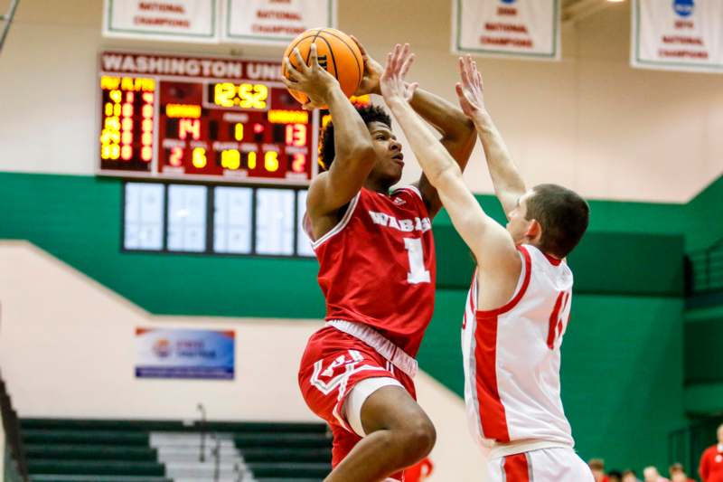 a basketball player in red uniform jumping to block a basketball