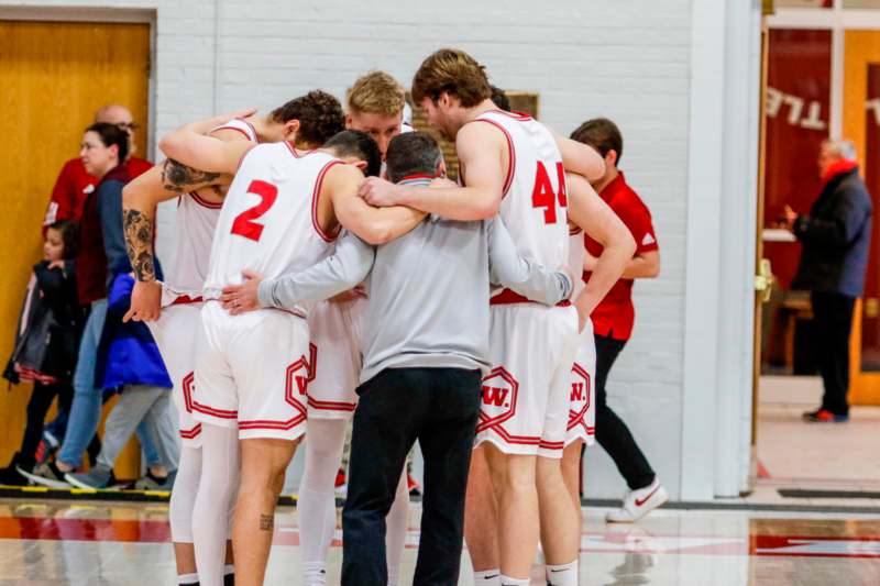 a group of men in a basketball team huddling