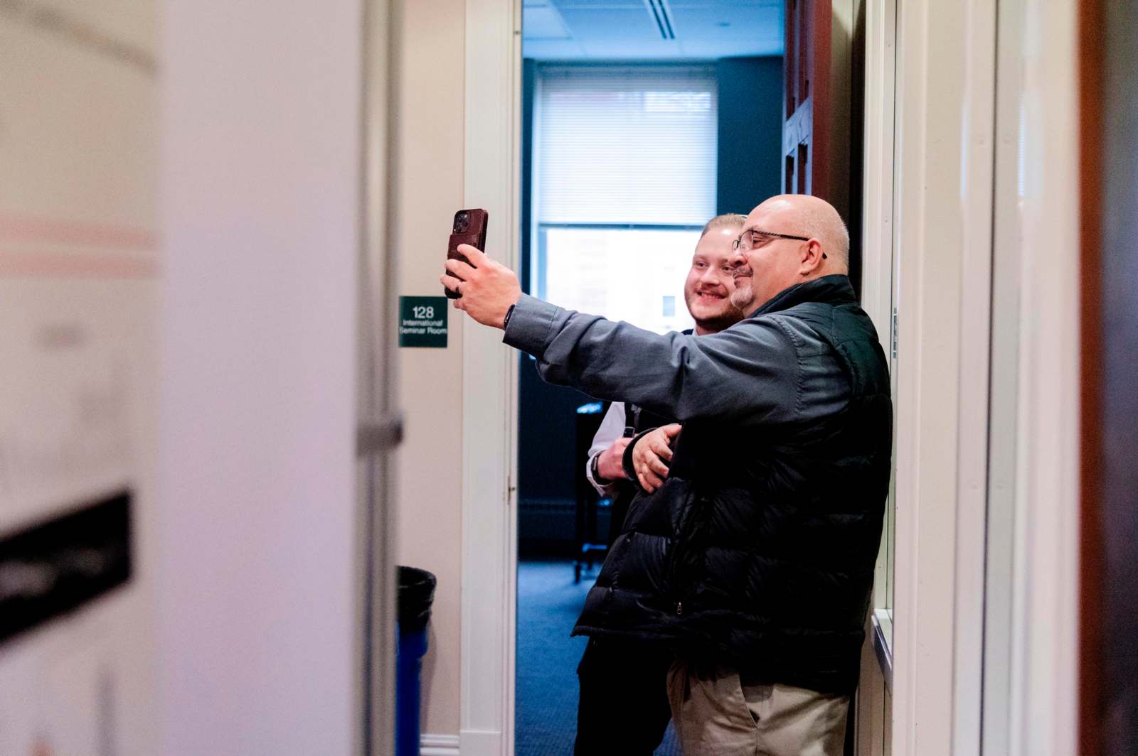 two men taking a selfie in a hallway