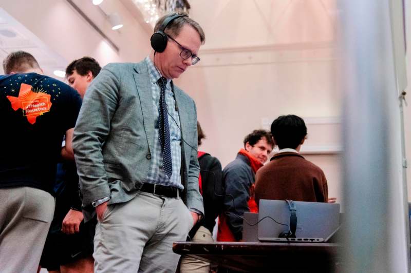 a man wearing headphones and standing in front of a laptop