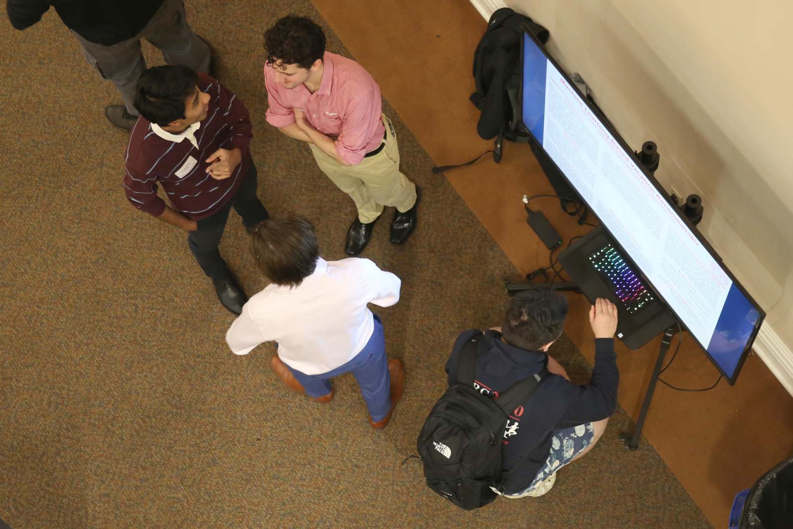 a group of men standing around a computer screen