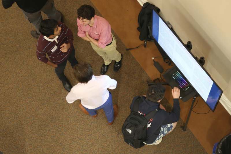a group of men standing around a computer screen
