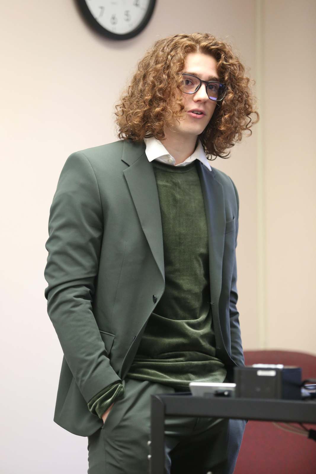 a man with curly hair wearing a suit and glasses
