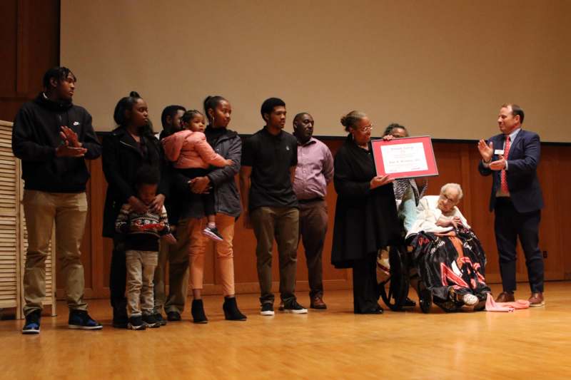 a group of people standing in front of a woman holding a certificate