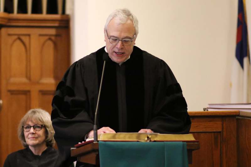 a man in a black robe standing at a podium