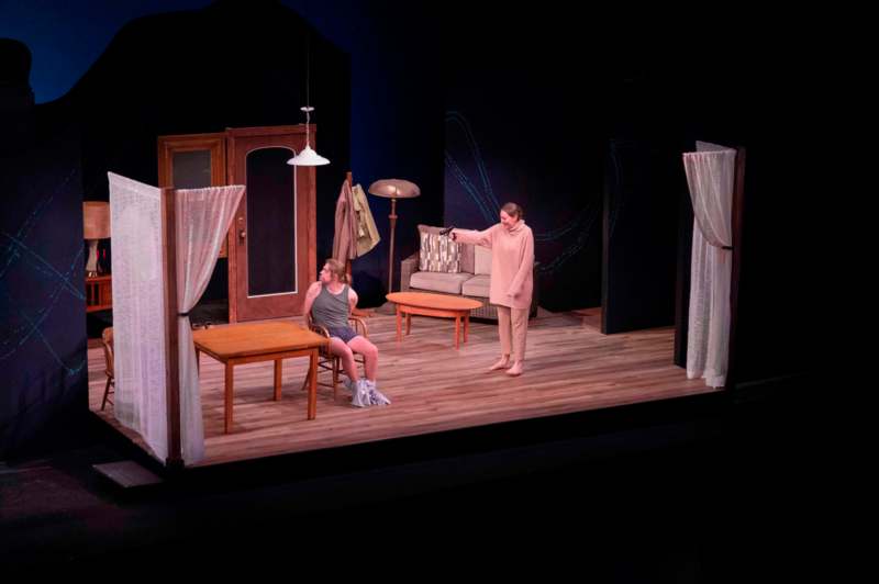 a woman sitting on a chair and a woman standing on a stage